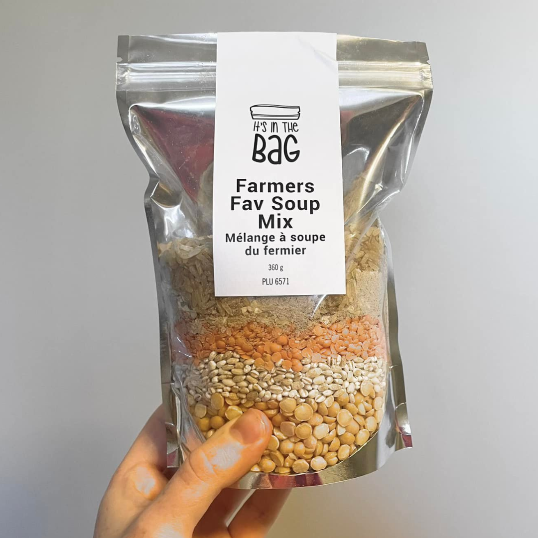 Packaged farmers' favorite soup mix with a clear bag showing ingredients, held by a hand against a neutral background.