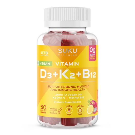 A bottle of SUKU Vitamins Vitamin D3 + K2 + B12 gummies with a yellow and orange label. The front reads “Supports Bone, Muscle and Immune Health” and highlights “2000 IU Vegan D3, K2 (MK7), Methyl B12.” It also shows “0g Sugar & Sugar Alcohol,” “50 Pectin Gummies,” and icons for gluten-free, vegan, and tree nut-free. A fruit illustration of lemon and dragon fruit appears in the corner.