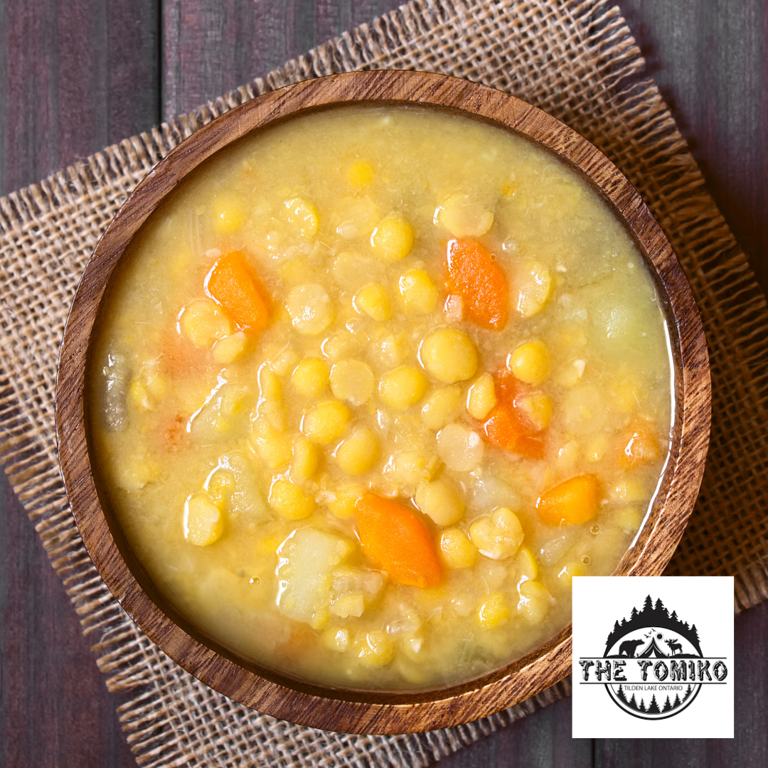 Corn chowder in a wooden bowl with The Tomiko logo.