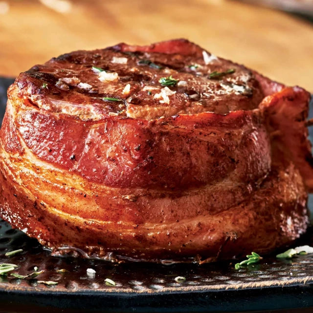 M&M meats bacon wrapped filet mignon on a dark plate. 