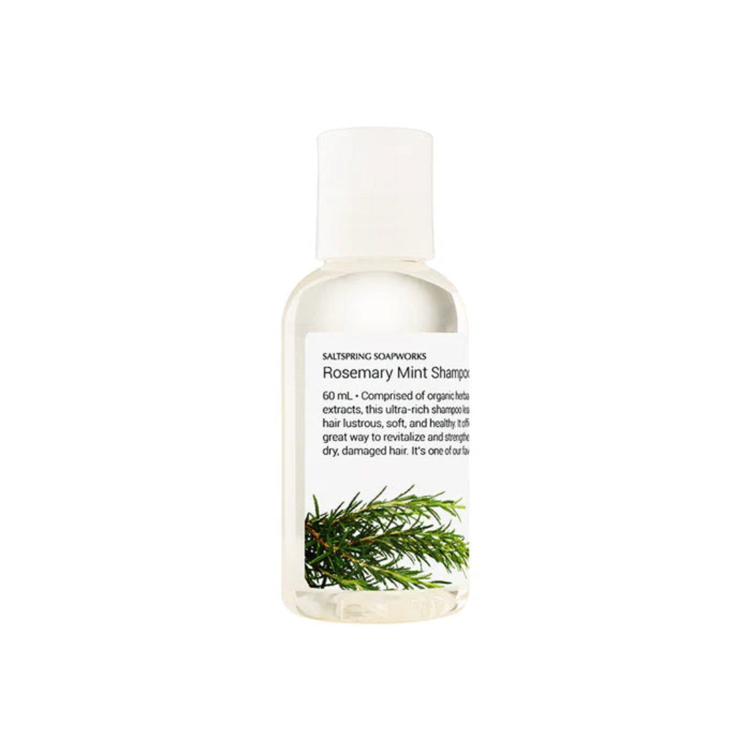 Bottle of Rosemary Mint Shampoo with green leaves on a white background